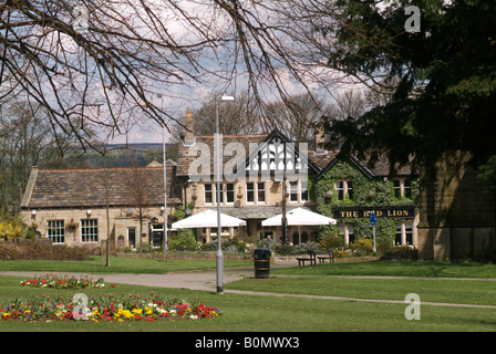 Le Red Lion Inn vu au-delà des fleurs et des espaces verts dans la rue principale de Burley dans Wharfedale Banque D'Images