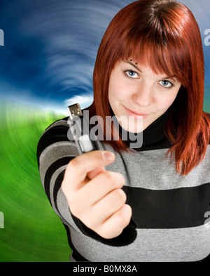 Belle jeune fille rousse tenant un bâton de mémoire USB ou un lecteur flash à l'appareil photo Studio shot Banque D'Images