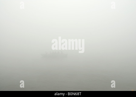 Batelier sur le Gange rangées le long du ghats dans morning mist, Varanasi, Inde Banque D'Images