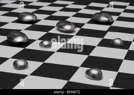 Conseil d'échecs avec galets en aluminium comme symbolisant la stratégie et le métal en fusion. Banque D'Images