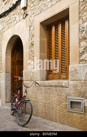 Un vélo contre un mur dans une rue de la ville de Pollensa, Majorque, Espagne. Banque D'Images