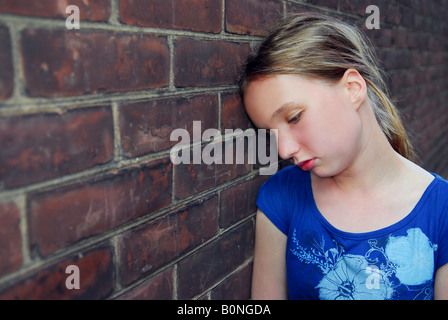 Jeune fille près de mur de brique à la colère Banque D'Images