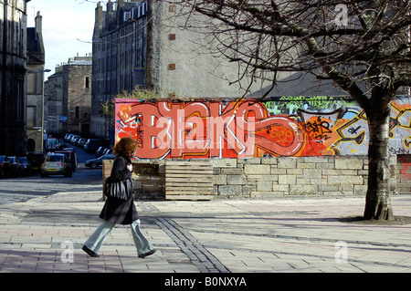 Une femme marche passé avec graffiti en toile de fond une scenic centre d'Édimbourg Banque D'Images