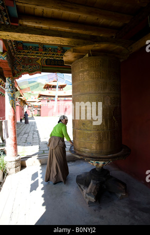 Les femmes tibétaines tournant grand moulin à prière dans le monastère bouddhiste Banque D'Images