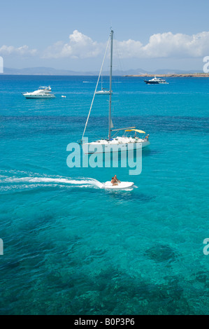 Un couple sur un bateau avec un yachts derrière eux Banque D'Images