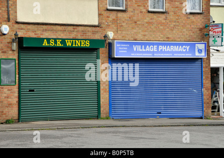 Sécurité volet roulant couvre en usage sur boutique de vins et de pharmacie dans les petits village shopping parade Banque D'Images