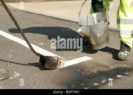 Marquage routier, piste de route, garder à l'écart, Santé et sécurité, peinture de route, Hommes au travail, peinture pour chariot, marqueur de ligne, suivant la ligne de trottoir, repère jaune. Banque D'Images