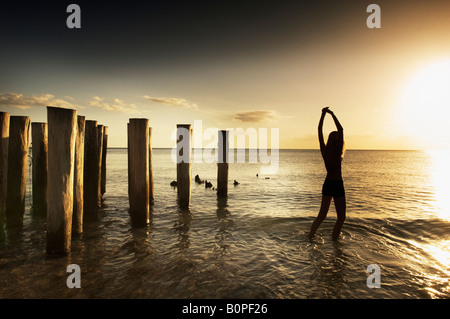 Silhouette d'une jeune femme jouant dans les vagues de l'océan près des quais Banque D'Images