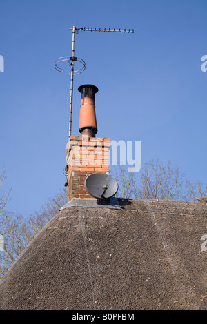 Antenne parabolique sur le toit de chaume à côté d'une antenne montée plat Ariel. Banque D'Images