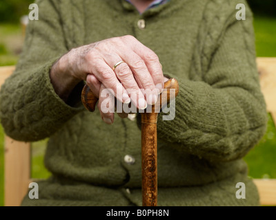 Vieil homme assis avec ses mains sur une canne Banque D'Images