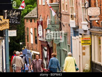 Les touristes en descendant la colline raide dans l'ancienne vieille ville au-delà d'un salon de thé traditionnel de Lincoln, Angleterre, RU Banque D'Images