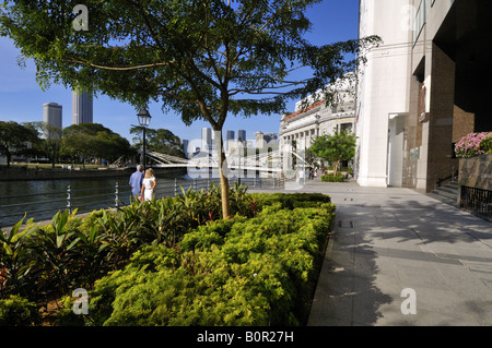 Un Caucasian couple walking down Boat Quay par rivière Singapour vers Fullerton Hotel. Banque D'Images