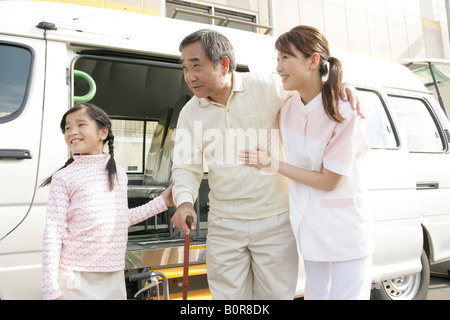 Girl aider grand-père appuyé par infirmière Banque D'Images