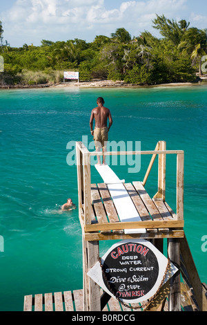 Un homme est prêt à plonger dans une eau de mer exotiques tout en un signe d'avertissement est pour courant fort Banque D'Images