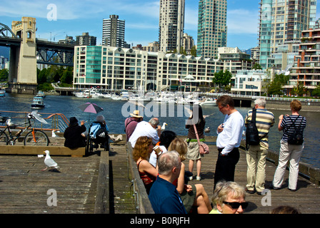 Les Vancouvérois et les touristes profitant d'une chaude journée ensoleillée sur le grand quai de False Creek waterfront sur Granville Island. Banque D'Images