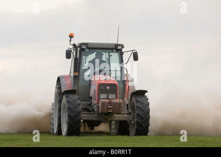 Tracteur Massey Ferguson de la traction d'une épandeuse de chaux qui s'étend à la pierre à chaux broyée pour aider à améliorer la fertilité des sols Banque D'Images