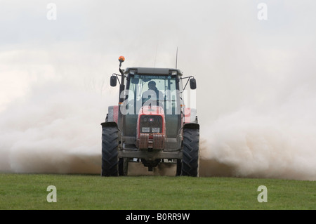 Tracteur Massey Ferguson de la traction d'une épandeuse de chaux qui s'étend à la pierre à chaux broyée pour aider à améliorer la fertilité des sols Banque D'Images