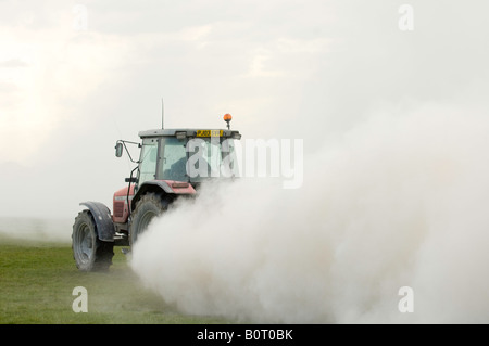 Tracteur Massey Ferguson de la traction d'une épandeuse de chaux qui s'étend à la pierre à chaux broyée pour aider à améliorer la fertilité des sols Banque D'Images