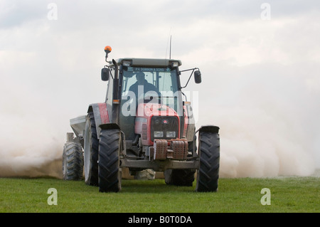 Tracteur Massey Ferguson de la traction d'une épandeuse de chaux qui s'étend à la pierre à chaux broyée pour aider à améliorer la fertilité des sols Banque D'Images