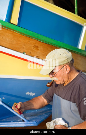 Bateau de pêche maltais traditionnel; pêcheur repeignant un oeil de Luzzu d'Horus ou d'Osiris sur le front pour protéger les pêcheurs lorsqu'ils sont en mer. Banque D'Images