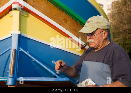 Bateau de pêche maltais traditionnel; pêcheur repeignant un oeil de Luzzu d'Horus ou d'Osiris sur le front pour protéger les pêcheurs lorsqu'ils sont en mer. Banque D'Images