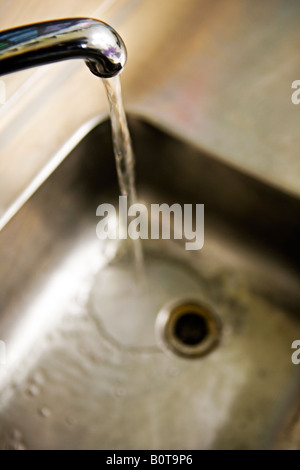 L'eau fonctionne à partir de puiser dans l'évier en acier inoxydable Banque D'Images