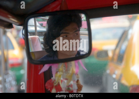 Un conducteur se reflète dans le rétroviseur d'un taxi Auto Rickshaw, communément appelé Tuk Tuk à Bangkok en Thaïlande Banque D'Images