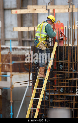 Porter l'équipement de sécurité complet du travailleur et le faisceau de l'échelle d'escalade sur un chantier de construction Banque D'Images