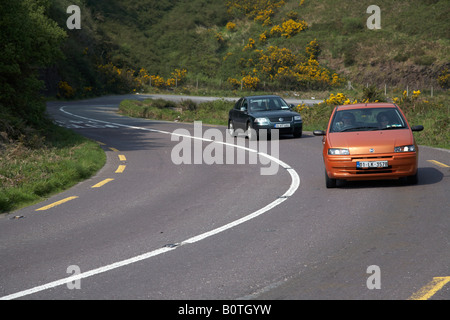 Voitures sur une section courbe étroite twisy de la principale route touristique route qui serpente à travers champs de la péninsule de Dingle en route vers di Banque D'Images