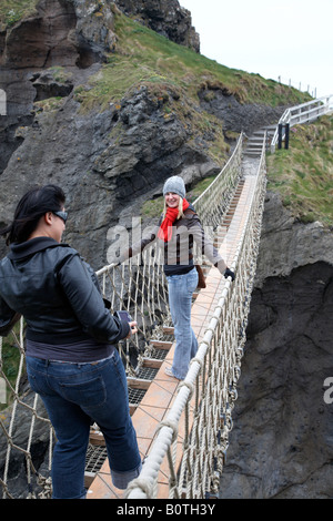 Deux femmes touristes posant sur le carrick a rede Rope Bridge sur le comté d'Antrim Coast Irlande du Nord Banque D'Images