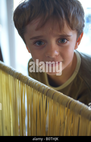 Garçon enfant à la rampe au drapé de pâtes fraîchement préparées Banque D'Images