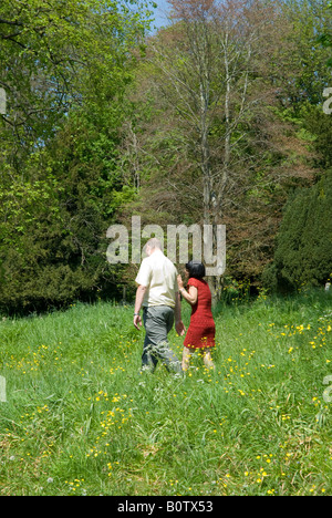 Couple marche loin dans les hautes herbes et fleurs sauvages. Des vêtements décontractés et robe rouge Banque D'Images