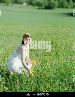 Jeune femme cueillette des fleurs dans un champ