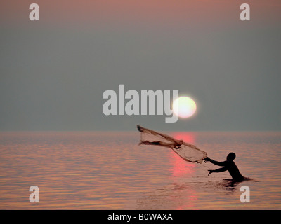 Dans la baie du pêcheur casting son filet sous le soleil couchant, l'île de Lombok, Indonésie, Îles de la sonde Lesser Banque D'Images