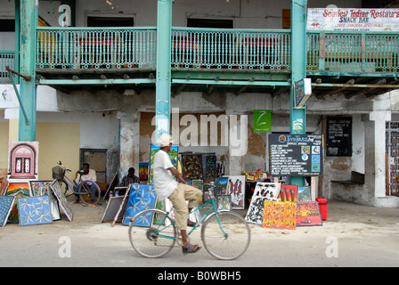 Scène de rue, cyclist riding passé un vieux bâtiment à Stone Town, Zanzibar, Tanzania, Africa Banque D'Images