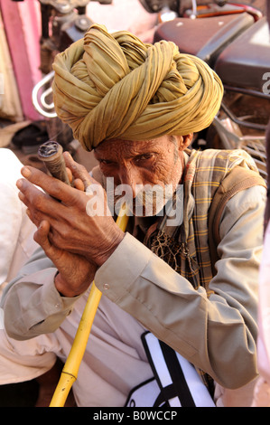 Un homme fume un Rajasthani traditionnelle pipe Chillum en Inde Banque D'Images