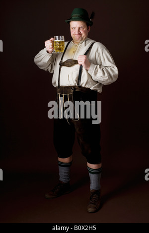 Les stéréotypes l'Allemand man in Bavarian costume raising a beer dans toast Banque D'Images