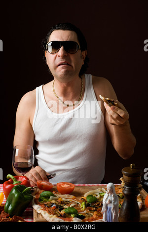 Man Eating pizza italienne stéréotypées et tenant un couteau Banque D'Images