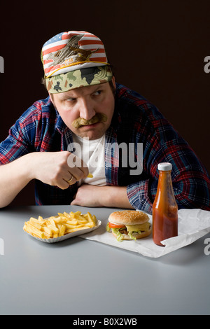 L'homme américain stéréotypé de manger un fast-food Banque D'Images