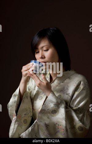 Une femme dans un kimono de boire du thé Banque D'Images