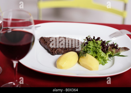 Still Life, la plaque de steak et des pommes de terre bouillies, rempli de verre de vin rouge Banque D'Images