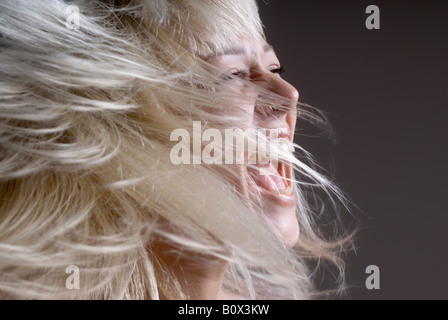 Une femme rejetant ses cheveux avec sa bouche ouverte Banque D'Images