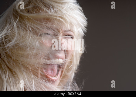Une femme rejetant ses cheveux avec sa bouche ouverte Banque D'Images
