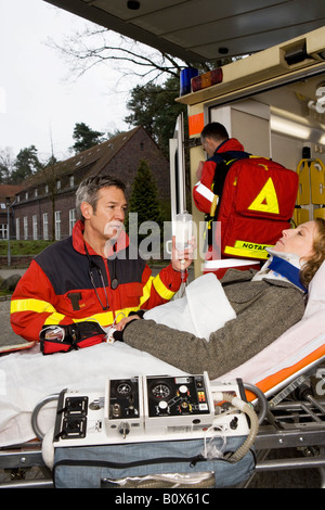 Deux ambulanciers paramédicaux et un patient allongé sur une civière à l'hôpital Banque D'Images