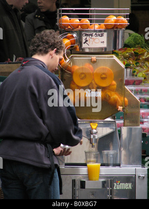 L'homme tire du jus d'orange avec une presse sur le Borough Market, London, Royaume-Uni Banque D'Images