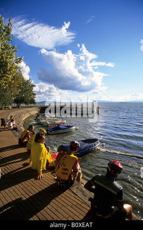 Italie Ombrie Passignano sul Trasimeno gens assis au bord du lac Banque D'Images