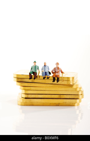 Figurines en plastique assis sur des lingots d'or Banque D'Images