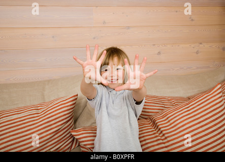 Boy (8-9) montrant tous les dix doigts at camera, smiling, portrait Banque D'Images