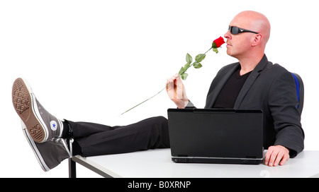 Businessman, occasionnels assis dans un costume de bureau et ordinateur portable, en tenant une odeur sur une rose Banque D'Images