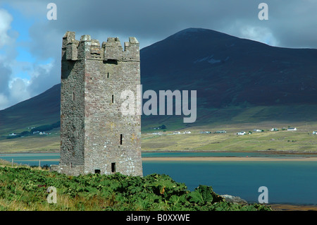 Une ancienne tour du château ruine sur Achill Island (Irlande) sur une journée ensoleillée, à l'arrière-plan une grande colline sur le continent avec un iris Banque D'Images